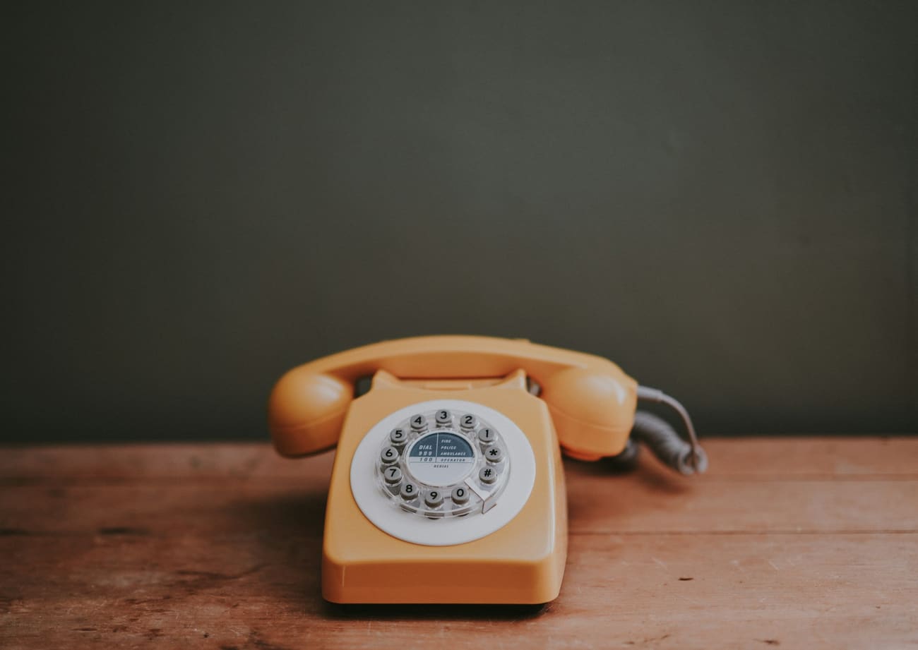 هاتف دوّار قديم على سطح خشبي دافئ — A vintage rotary telephone on a warm wooden surface